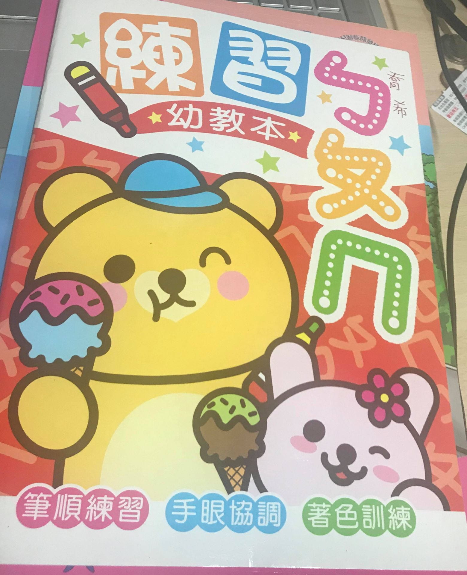 A children's practice book with a light brown bear and pink rabbit eating ice cream 
